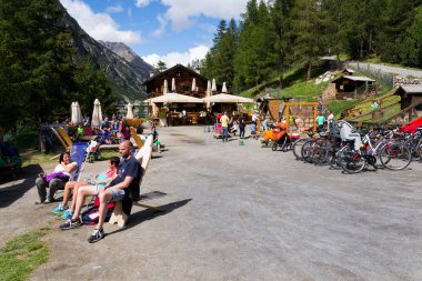 Livigno, İtalya - 1 Ağustos: çocuklar ve bisiklet Livigno, İtalya 1 Ağustos 2016 Lago di Livigno banka üzerinde oynamak ile restoran önünde güneşlenme insanlar.