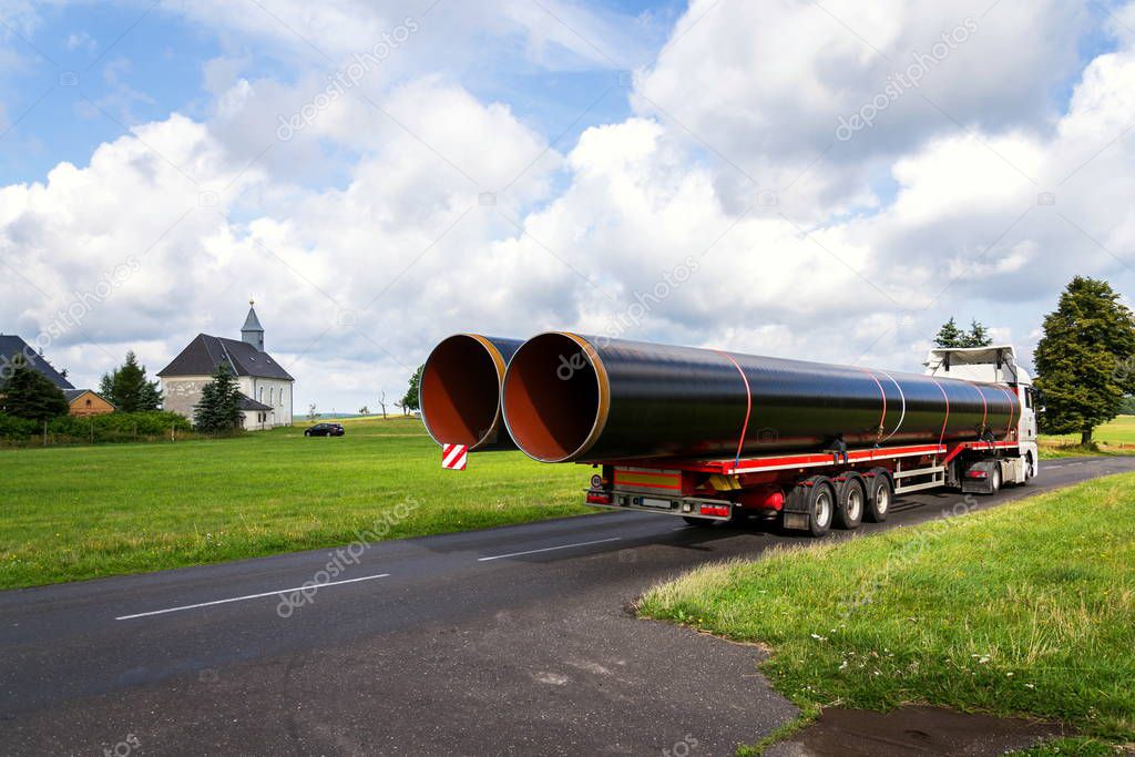 Truck transporting large steel oil and gas pipes, excessive load and heavy delivery concept