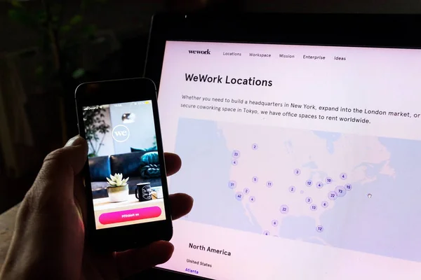 Prag, Tschechische Republik - 19. Dezember 2019: wework Gewerbeimmobiliengesellschaft App auf dem Telefonbildschirm mit Internet-Seite im Hintergrund am 19. Dezember 2019 in Prag, Tschechische Republik. — Stockbild Prag Tschechische Republik Dezember 2019 Wework Gewerbeimmobiliengesellschaft App Auf Dem — Stockfoto