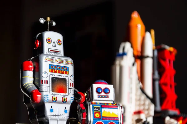 Vintage tin toy robot looking into the future of space exploration with rocket in background, artificial intelligence and space tourism concept