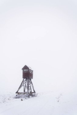 Geyik duruşu, ahşap avcılar yüksek koltuk karla kaplı tarlada saklanmak, kış sisli günü