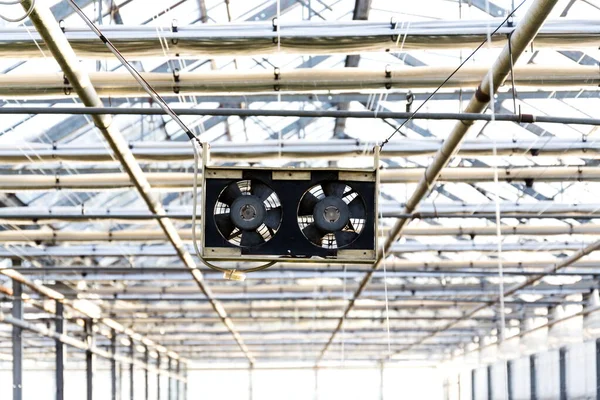 Pair of black small fans under the roof of a greenhouse, air-conditioning, heat wave or global warming concept