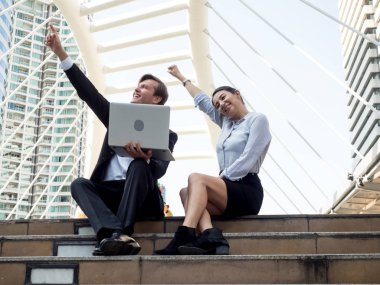 İş adamları ve kadınlar bir defter tutarak, el kaldırarak, yatırım, araştırma, arama, dijital teknoloji üzerine proje toplantısından mutlu olurlar.