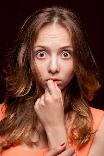 Surprised girl in an orange blouse on a dark background. — Stock Photo, Image