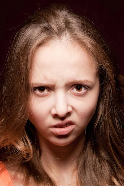 Angry girl face expression on dark background close up. — Stock Photo, Image