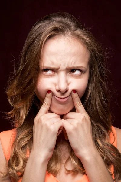 La chica hizo una expresión de cara malvada sobre un fondo oscuro —  Fotos de Stock