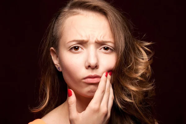 The girl is experiencing a toothache, close-up on a dark backgro — Stock Photo, Image