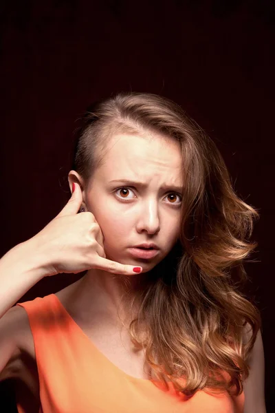 The girl makes a gesture with her hand call on a dark background — Stock Photo, Image