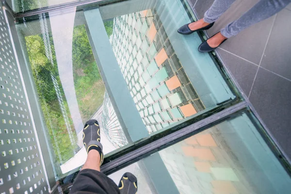 一幢高楼玻璃地板上的男女腿 — 图库照片