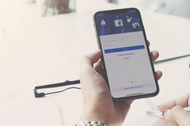 CHIANG MAI, THAILAND - MAR 7 2020: Facebook sosyal medya uygulaması logosu giriş, mobil uygulama ekranı için kayıt sayfası iPhone X 'de (10) kişinin elinde e-ticaret alışveriş otobüsleri üzerinde çalışıyor