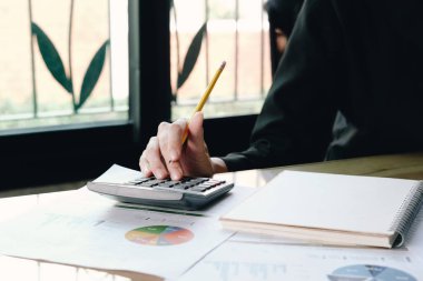 Hesap makinesi ve dizüstü bilgisayarı kullanarak ofis odasındaki ahşap masa ve iş geçmişi, vergi, muhasebe, istatistik ve analitik araştırma konsepti üzerinde matematik finansmanı kullanarak iş kadınlarını kapat