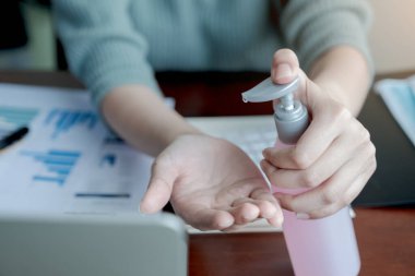 Coronavirus. Ofiste ellerini yıkayan bir kadın. Corona virüsü yüzünden maskeden hasta. Bilgisayarlı çalışma masası. Alkol jeli sıkan kadın ya da antibakteriyel sabun dezenfektanı