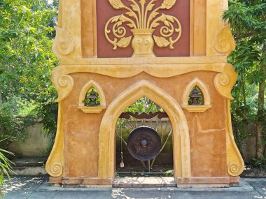Tayland 'da bir yerde metal gong ve kolon. Sarı ve kahverengi. Asya 'nın renkli mimarisi.