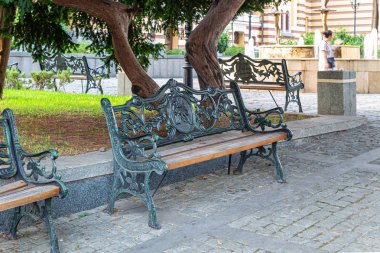 Şehir parkında ahşap koltuklu demir banklar dökün.