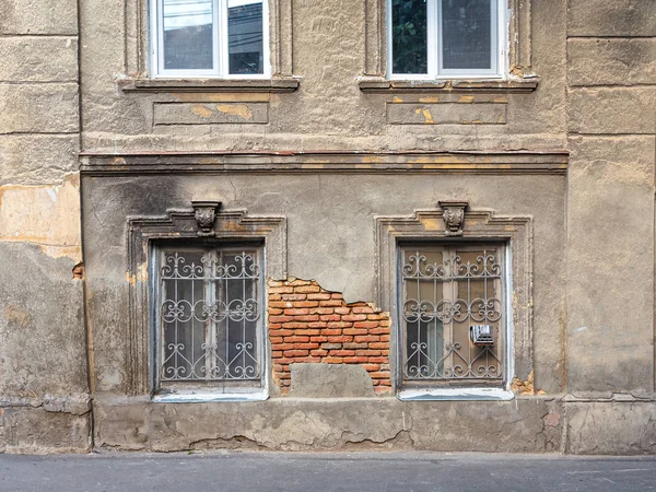 Janelas Barradas na parede de uma casa velha com gesso caído — Fotografia de Stock