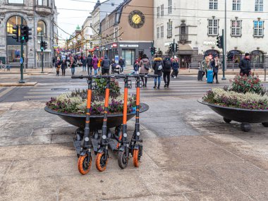 Turuncu scooterlar büyük bir dökme demir vazonun yanında sıra sıra bekliyor.