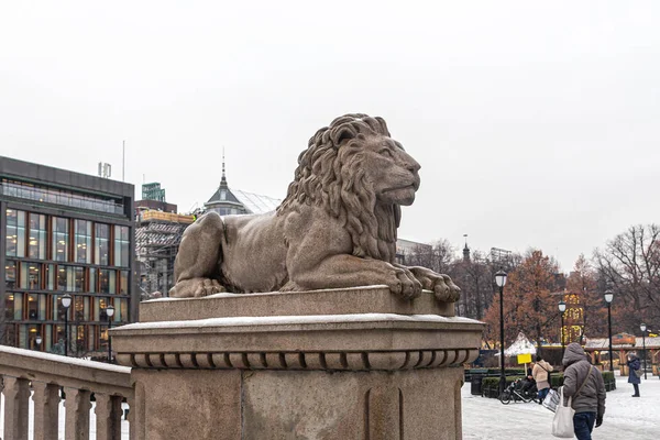 Kamienny lew na tle budynków i parku miejskiego — Zdjęcie stockowe