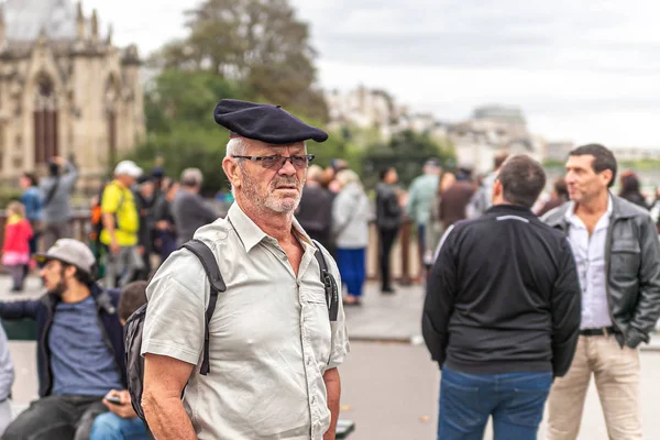 Ősz hajú férfi svájcisapkában, hátizsákkal a Notre-Dame katedrálisban. — Stock Fotó