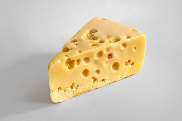 Triangular piece of Maasdam cheese with large holes
