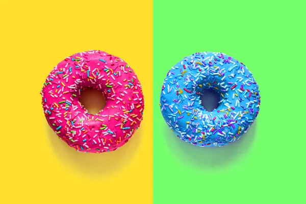 Dois donuts vitrificados rosa e azul em fundos multicoloridos — Fotografia de Stock