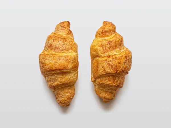 Due mini croissant con crosta dorata su fondo chiaro — Foto Stock