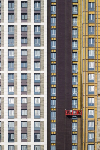 Trabalhador em altura em um berço de construção vermelho — Fotografia de Stock