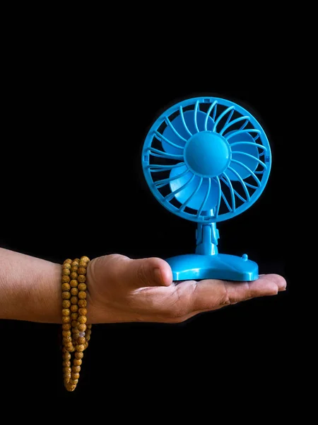 Hand with Buddhist beads and small electric fan