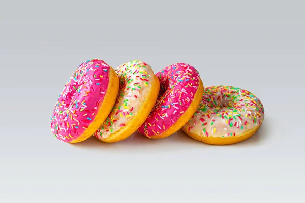 Four bright donuts with strawberry and vanilla icing and multicolored topping — Stock Photo, Image