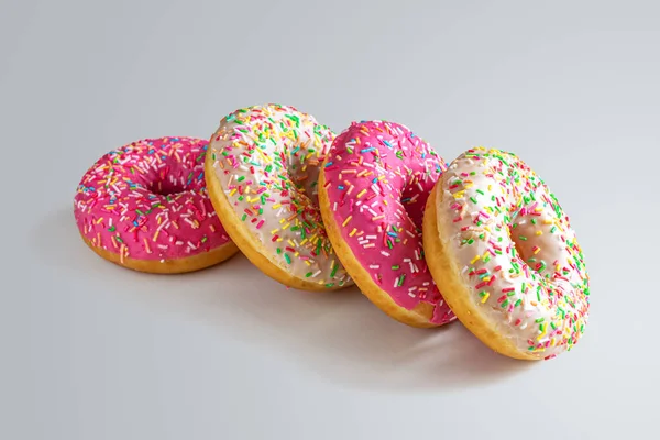 Four glazed donuts on a light gray background — Stok fotoğraf