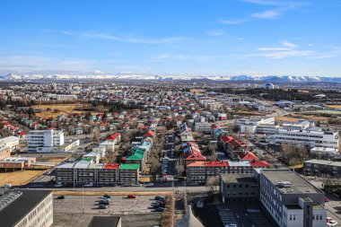 Reykjavik, İzlanda, 03.29.2018. Hallgrimskirkja Lutheran Kilisesi 'nin gözlem güvertesinden Reykjavik' in görüntüsü. Renkli çatıları ve ufukta karla kaplı dağları olan temiz evler.