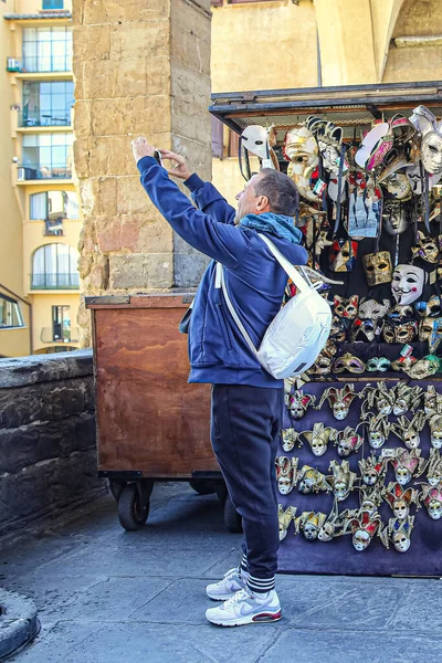 2018年3月26日 イタリア フィレンツェ 男性観光客はフィレンツェのマスクとカウンターの近くにあるヴェッキオ橋の上でスマートフォンで写真を撮ります — ストック写真