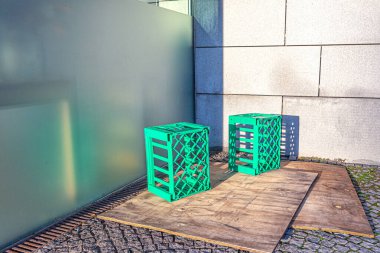 Yeşil plastik kutular taşımak ve depolamak için şişeler ahşap paneller üzerinde uzanır, evin duvarına karşı, sigara içme alanı