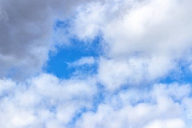 Güneşli bir bahar gününde mavi gökyüzü, beyaz bulutlarla kaplı. Rüzgar mavi gökyüzünde bulutlar savurur