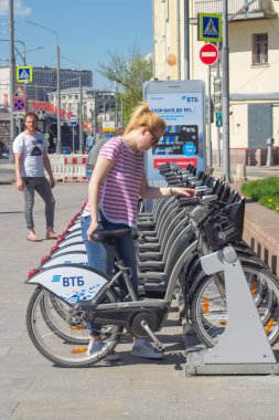 Moskova, Rusya, 05.08.2018. Kız Moskova 'da otomatik bisiklet parkında kendine bir bisiklet seçiyor.