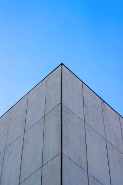 Mavi gökyüzüne karşı çatının üçgen silueti. Gri renkli beton levhalar. Evin açısı