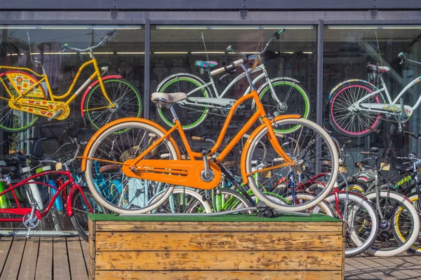自転車レンタル店の窓を背に木製の台座の上にオレンジの自転車 — ストック写真