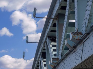 Gece aydınlatması için perçin ve fenerli çelik köprü yapısı bulutların arka planına ve mavi gökyüzüne karşı