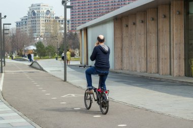 Bisiklet yolunda kapüşonlu, kot pantolonlu ve telefonda konuşan kel bir adama biniyordum.