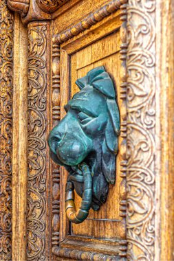 Ağzında yüzükle aslan başı şeklinde pirinç sapı olan açık ahşap bir kapı.