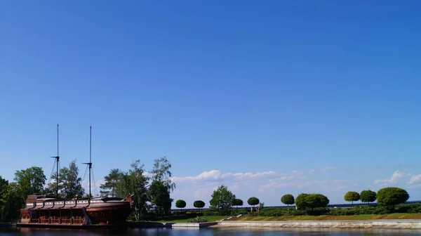 view of the river and a wooden ship. In the background a blue sky