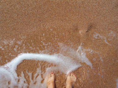 girl legs on the seashore with waves and foam