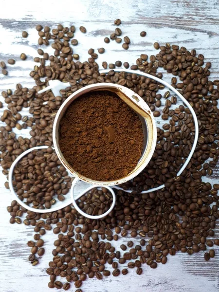 木のテーブルの上にコーヒーの挽いたコーヒーグラインダーのクローズアップ焼きたての茶色の芳香のあるコーヒー豆と背景 — ストック写真