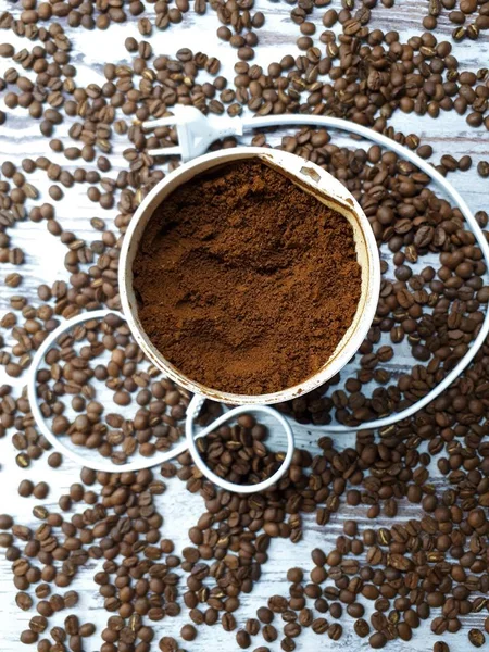 木のテーブルの上にコーヒーの挽いたコーヒーグラインダーのクローズアップ焼きたての茶色の芳香のあるコーヒー豆と背景 — ストック写真