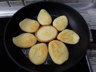  Kızartma tavasında krep yakın plan siyah bir sobanın üzerinde çiçek şeklinde.