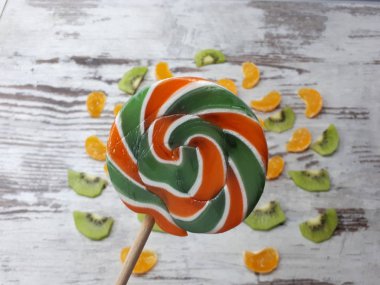 Dilimlerden, kivilerden, mandalinalardan oluşan büyük yuvarlak bir meyve lolipopunun yakın plan çekimi.