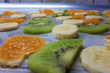  Dilimlenmiş kivi, mandalina / portakal, soyut ahşap bir yüzey üzerinde muz.