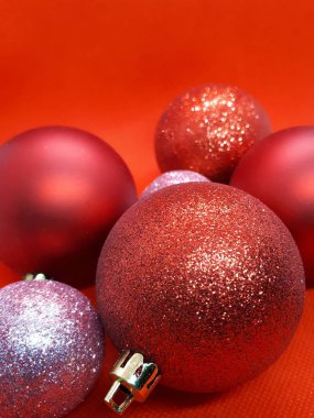 Noel ağacı için çok renkli şenlikli süslemeler, parlak kırmızı arka planda balolar ve hediyeler.