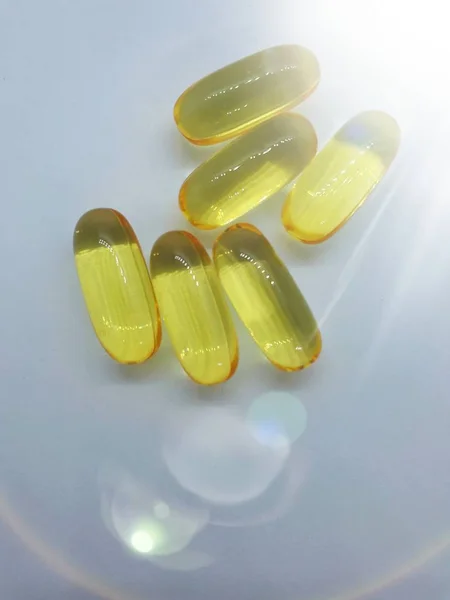 Zole Edilmiş Işık Arkaplanındaki Sarı Jelatin Kapsüllerinin Bir Ilaç Beslenme — Stok fotoğraf