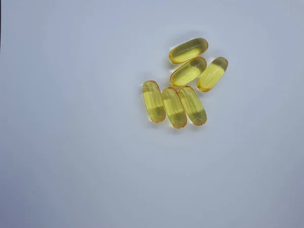 close-up of a medicine / dietary supplement, yellow gelatin capsules on an isolated light background