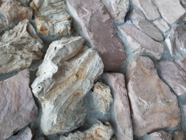 Bokeh efekti ve karakteristik kaba gözenekli dokusu, soyut koyu ve aydınlık lekeleri olan dekoratif bir duvarın yakın çekimi.